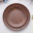 Brown wooden plates stacked on a table with elegant decor.