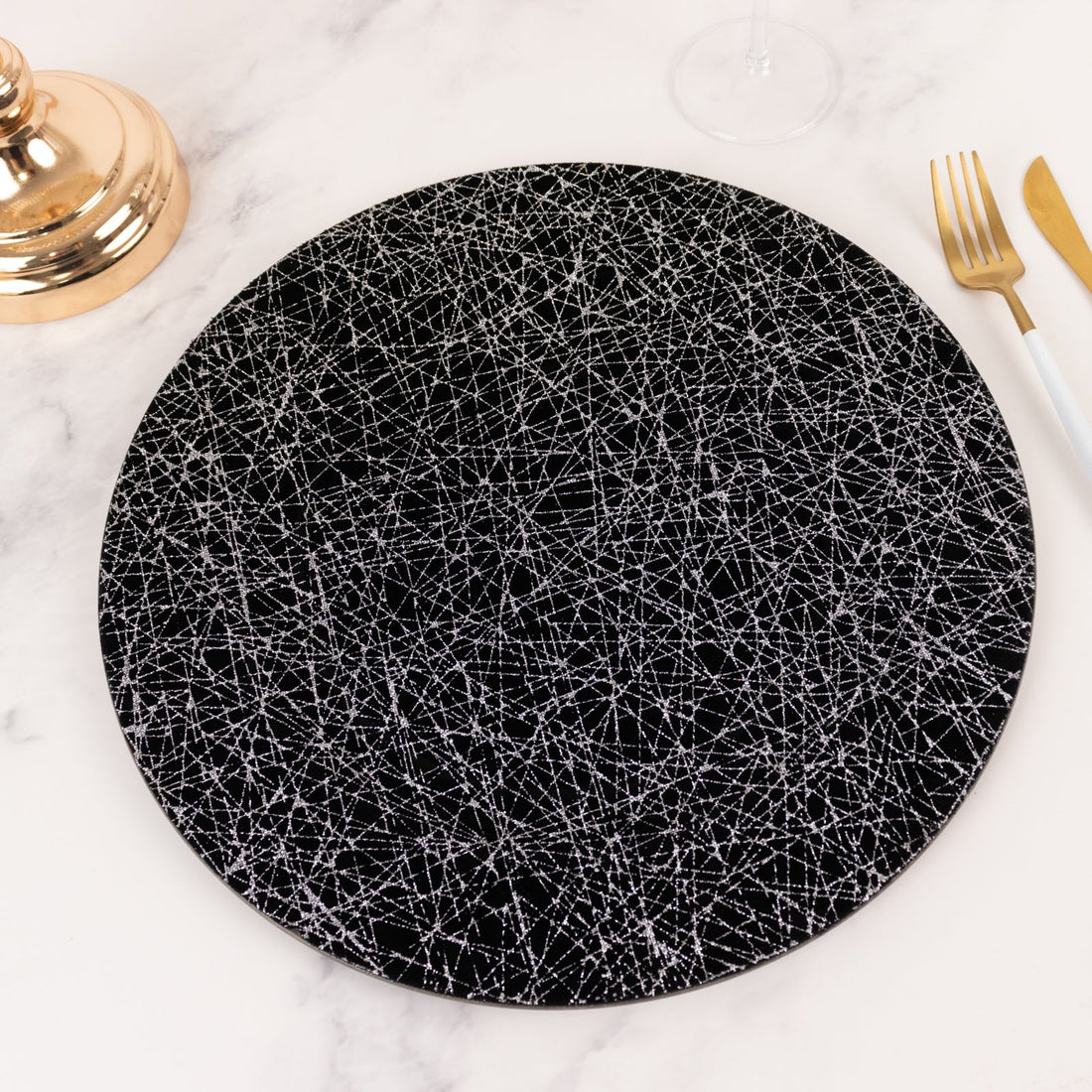 Black plate with abstract white line design on a marble surface.