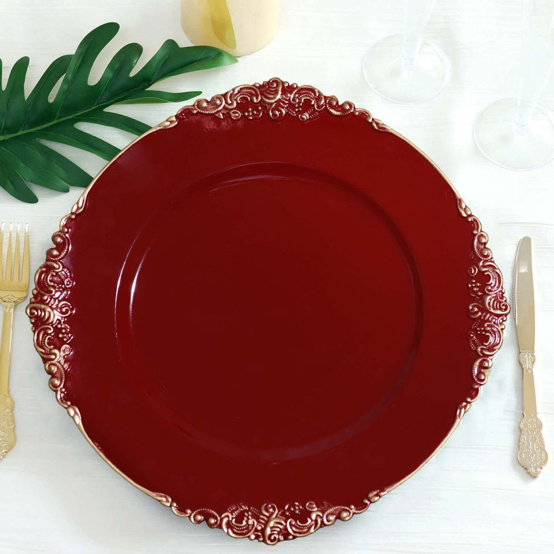 Elegant red decorative plate with gold accents on a table setting.