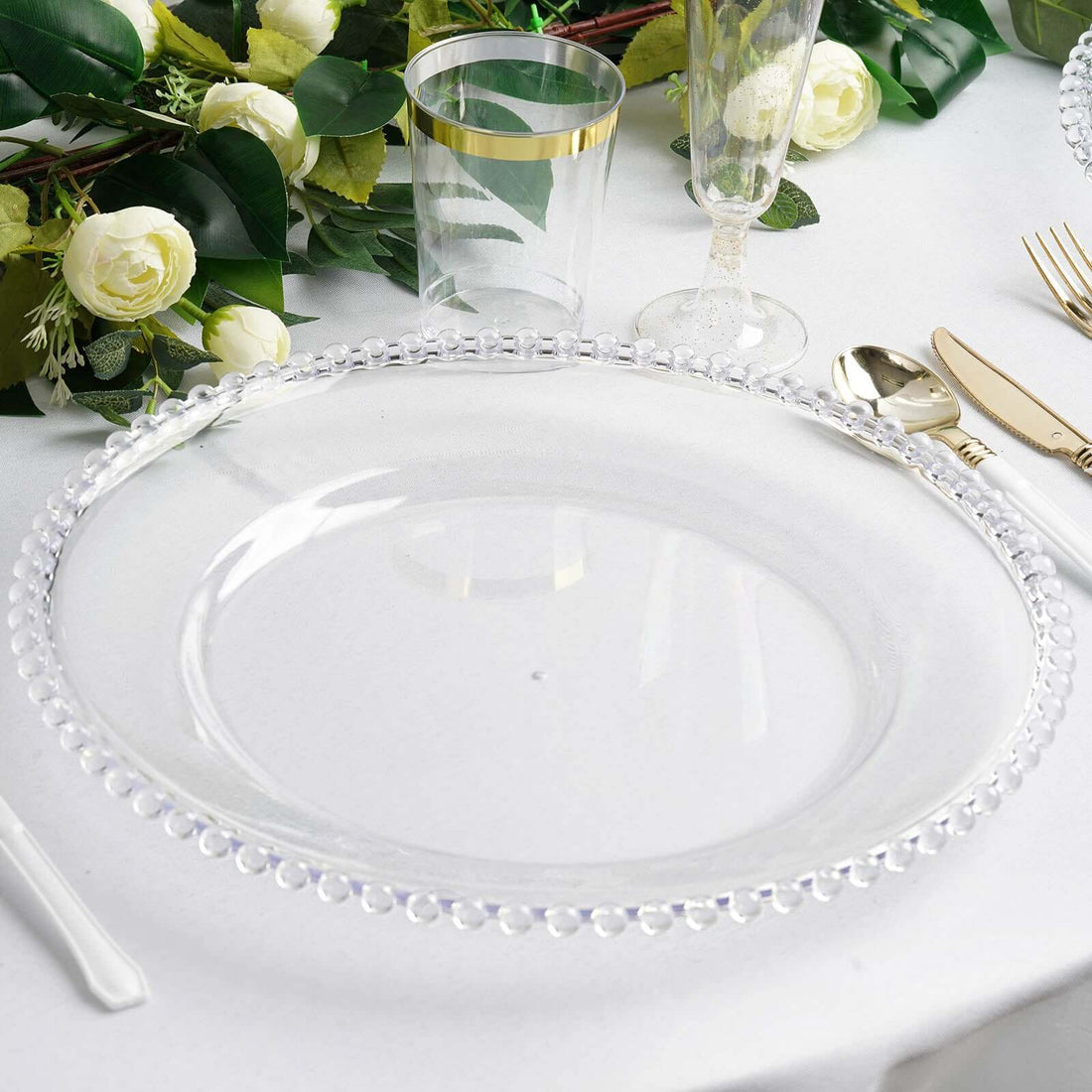 Clear decorative charger plate with beaded edge on a dining table setting.
