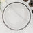 Clear glass plate with black beaded rim on marble surface.
