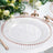 Clear glass charger plate with rose gold beaded rim on a dining table setting.