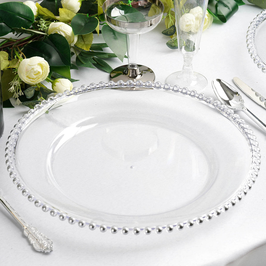 Clear charger plate with beaded rim on a table setting.