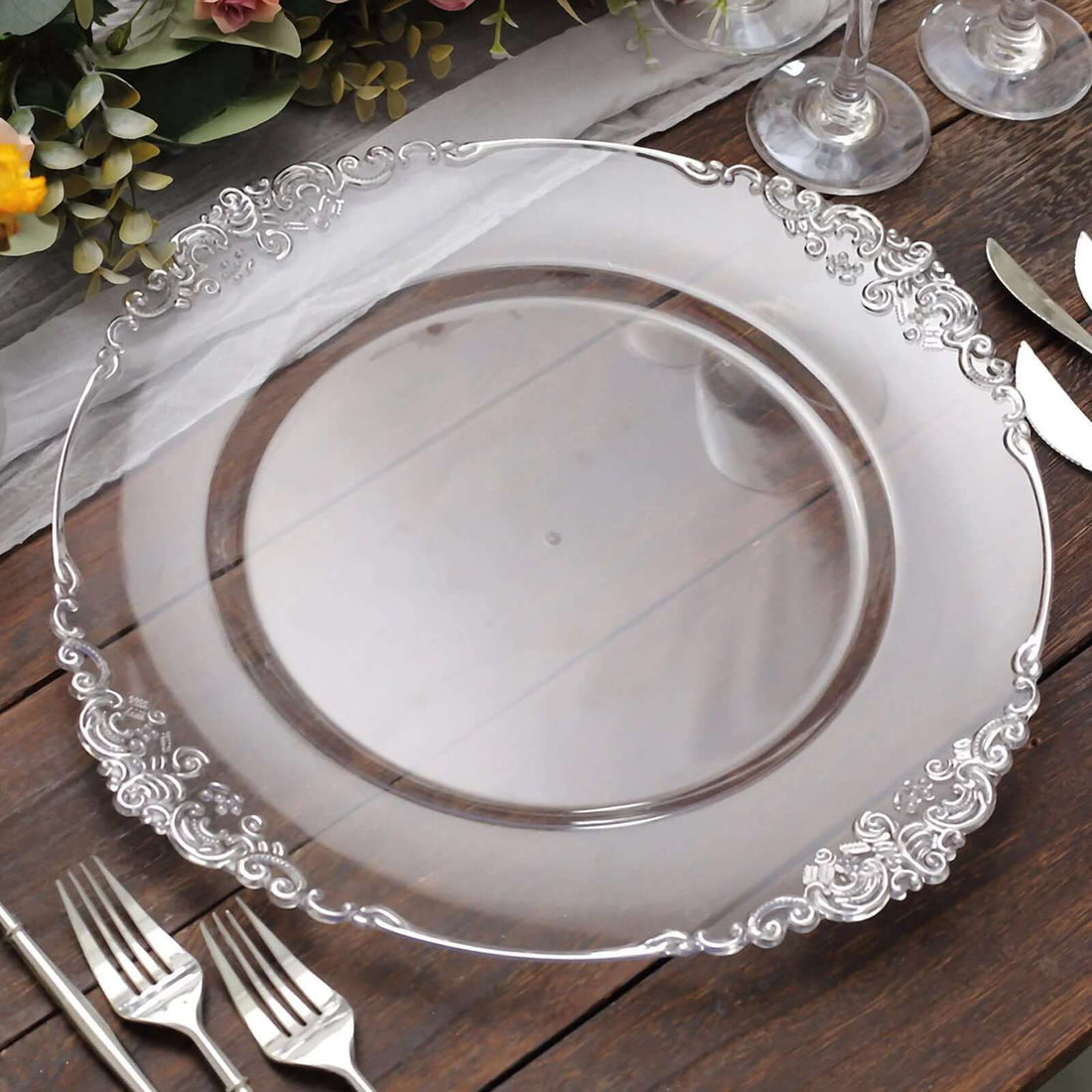 Elegant clear glass charger plate with ornate silver trim.