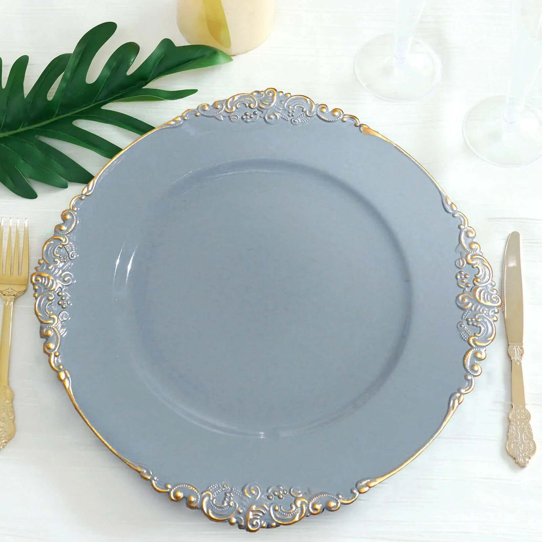 Elegant gray plate with gold detailing, surrounded by cutlery and greenery.
