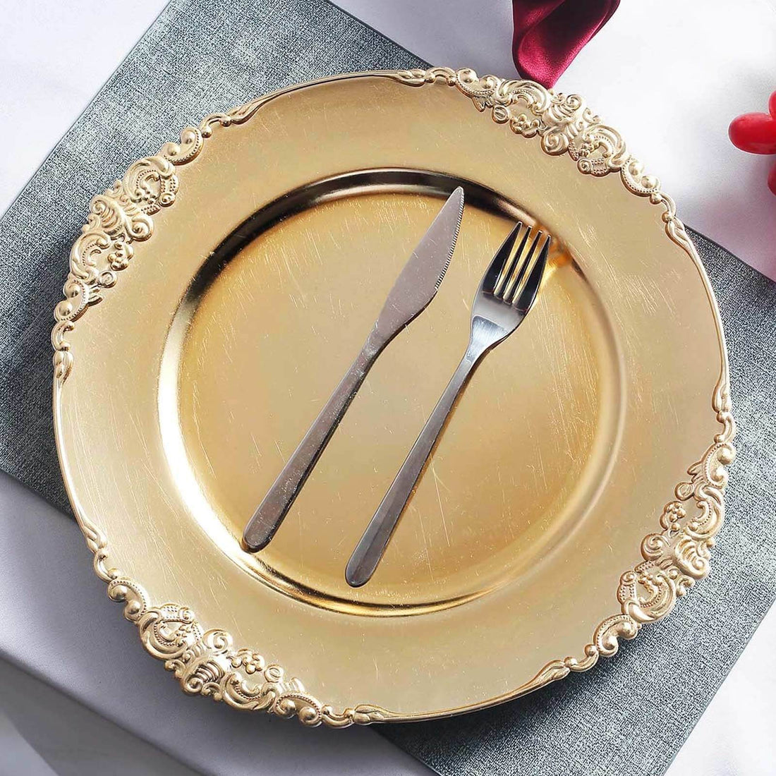Gold decorative plate with knife and fork on a textured tablecloth.