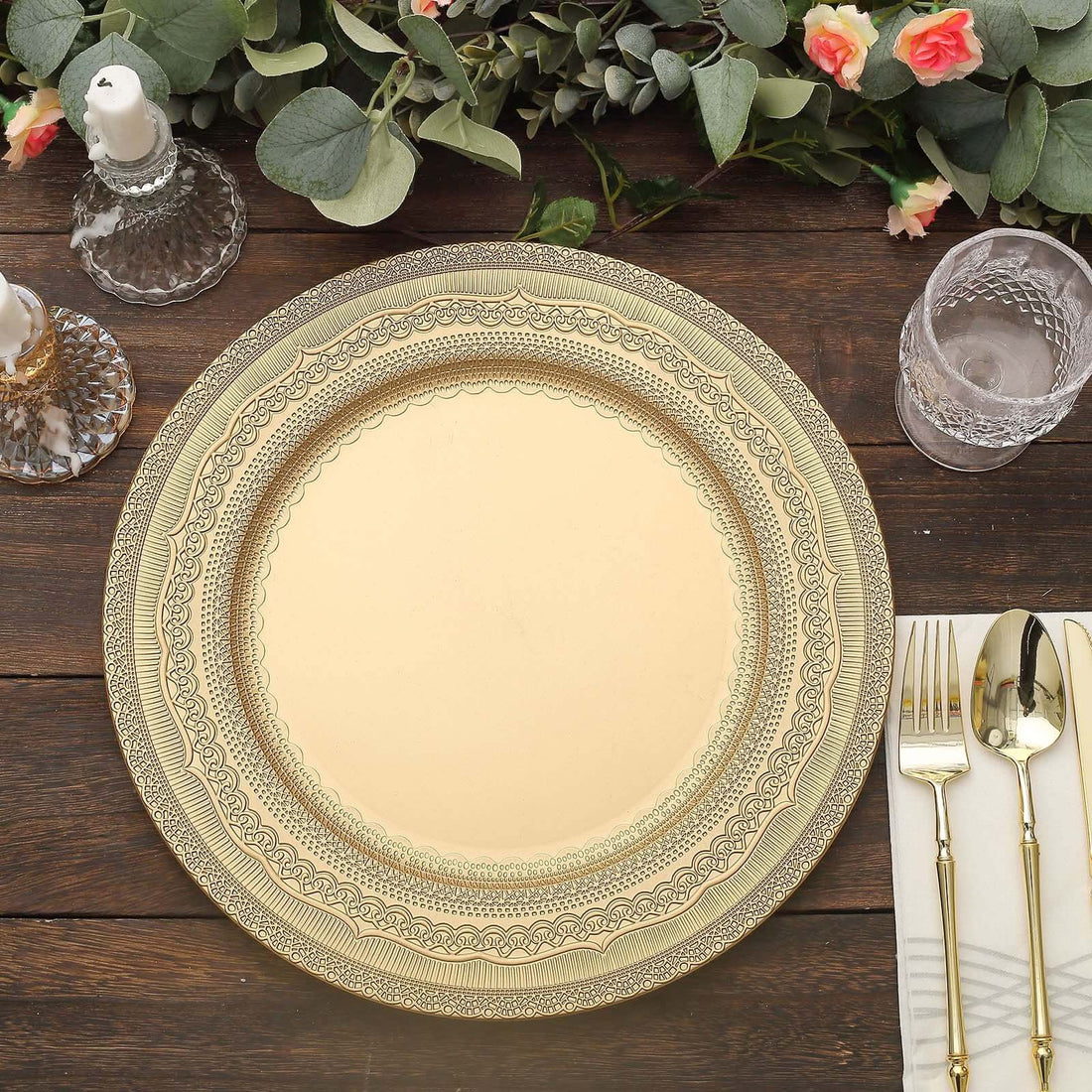 Elegant gold charger plate on a wooden table with floral accents and glassware.