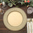 Elegant gold charger plate on a wooden table with floral accents and glassware.