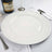White decorative plate on a dining table with champagne and silverware