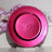 Pink decorative charger plate with beaded trim against a soft floral backdrop.
