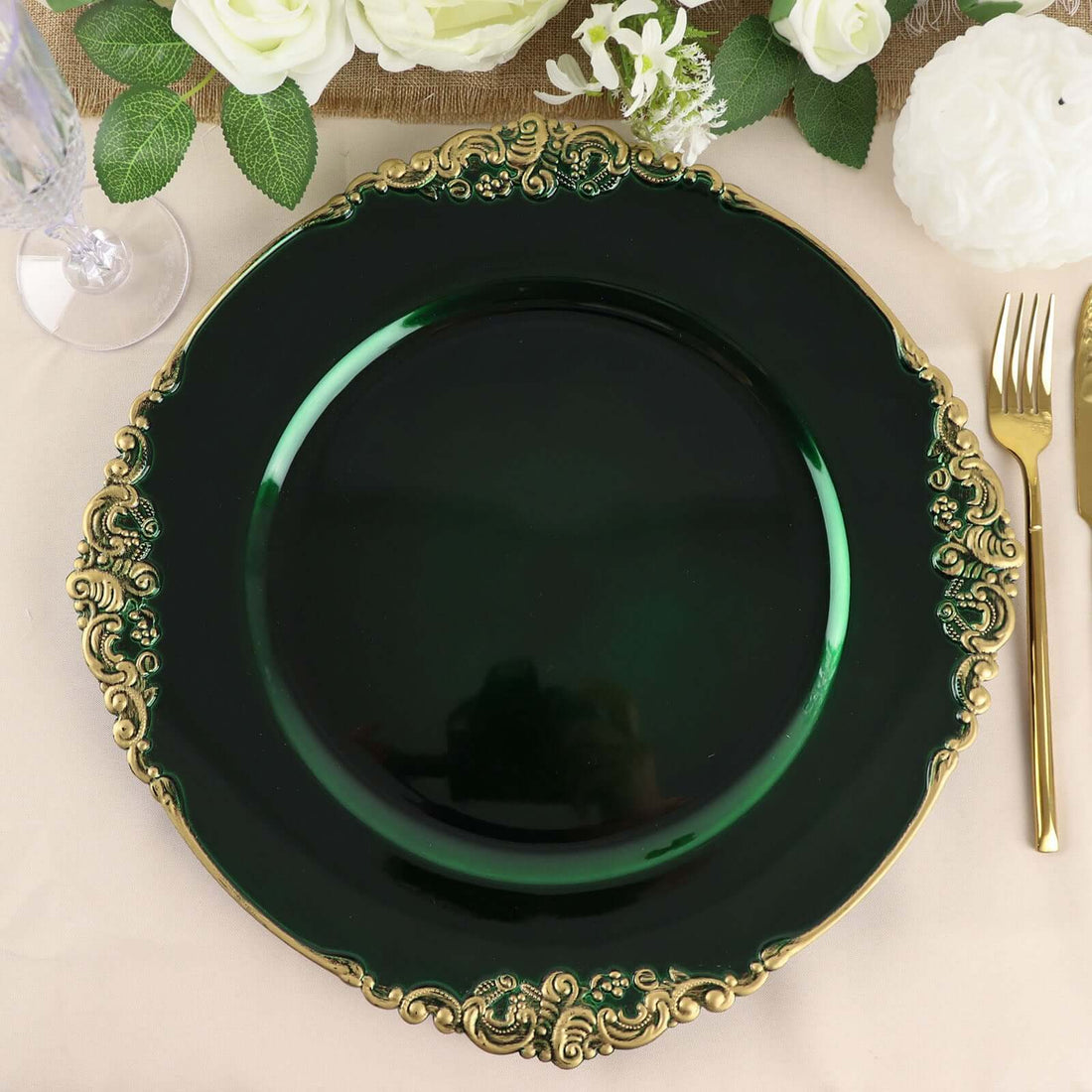 Elegant green charger plate with ornate gold trim on a dining table setting.