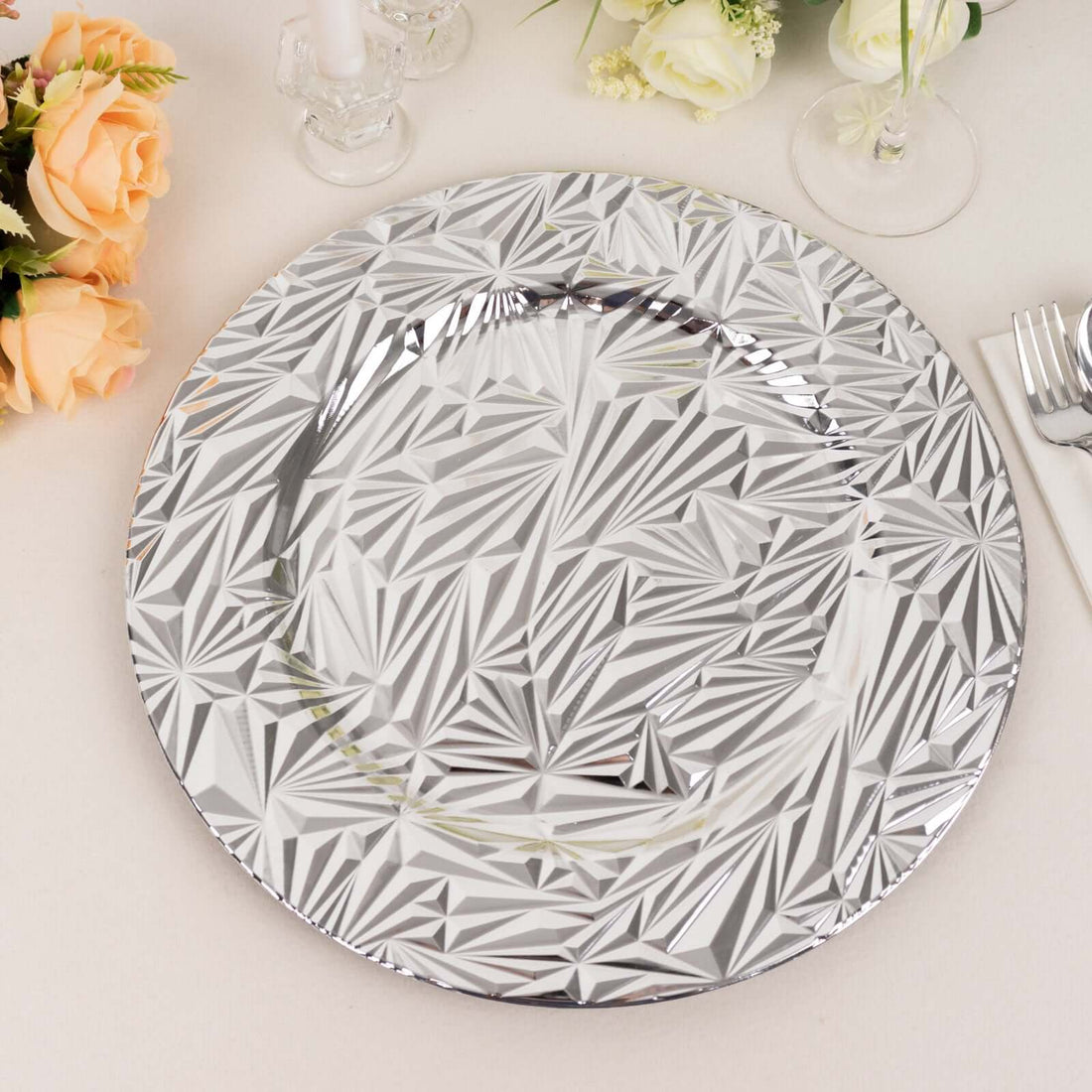 Silver decorative plate with geometric patterns on a table setting.