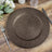 Textured brown decorative charger plate on a wooden table setting.