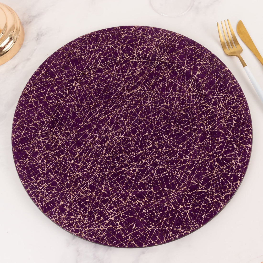 Purple round plate with gold abstract design on a marble surface.