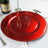 Red charger plate on a dining table with champagne and elegant cutlery.