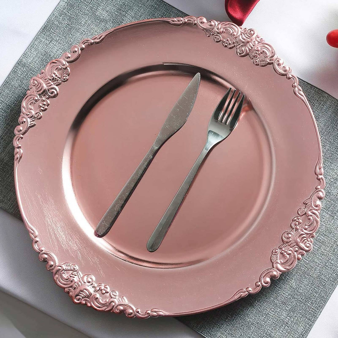 Rose gold decorative plate with a knife and fork on a table setting.
