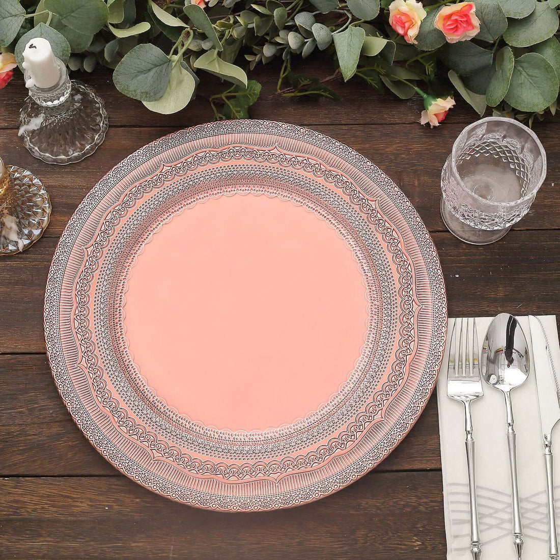 Decorative pink plate with intricate silver detailing on a wooden table setting.