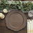 Rustic wooden charger plate on a table with greenery and candles.