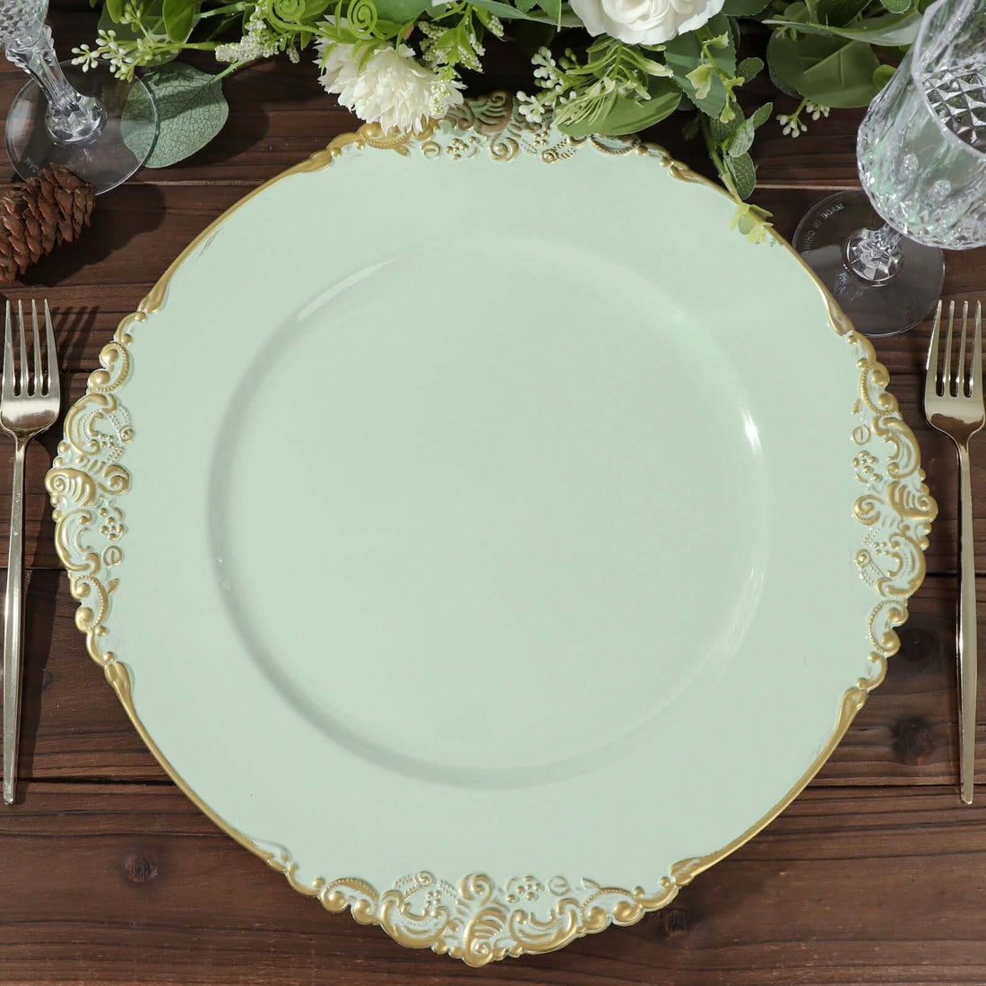 Elegant mint green plate with ornate gold trim on a wooden table setting.