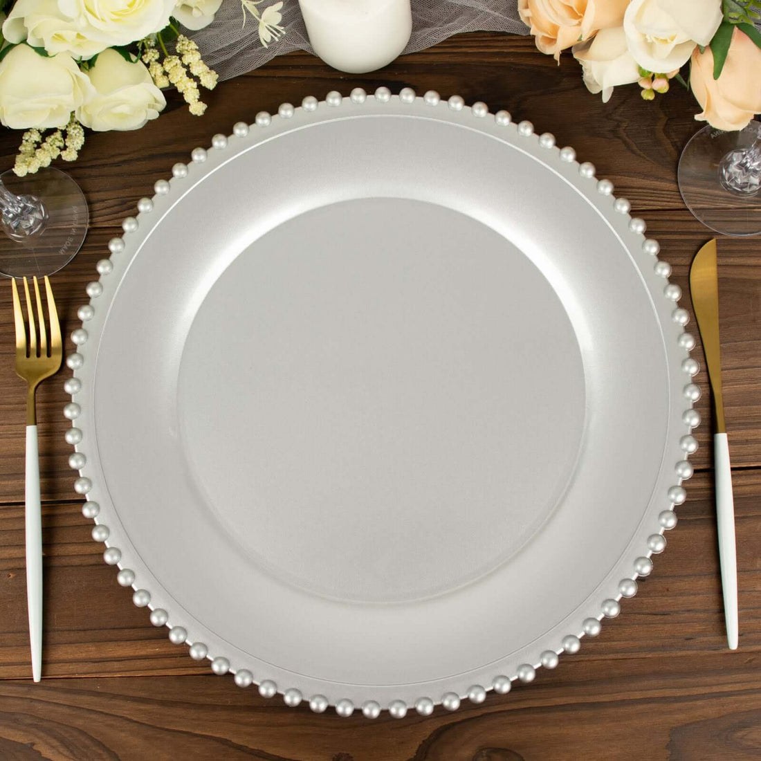 Silver charger plate with pearl rim on wooden table setting.