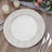 Decorative white serving platter on a wooden table with candles and flowers.