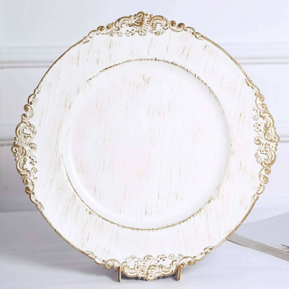 Elegant white plate with gold ornate edges on a stand.
