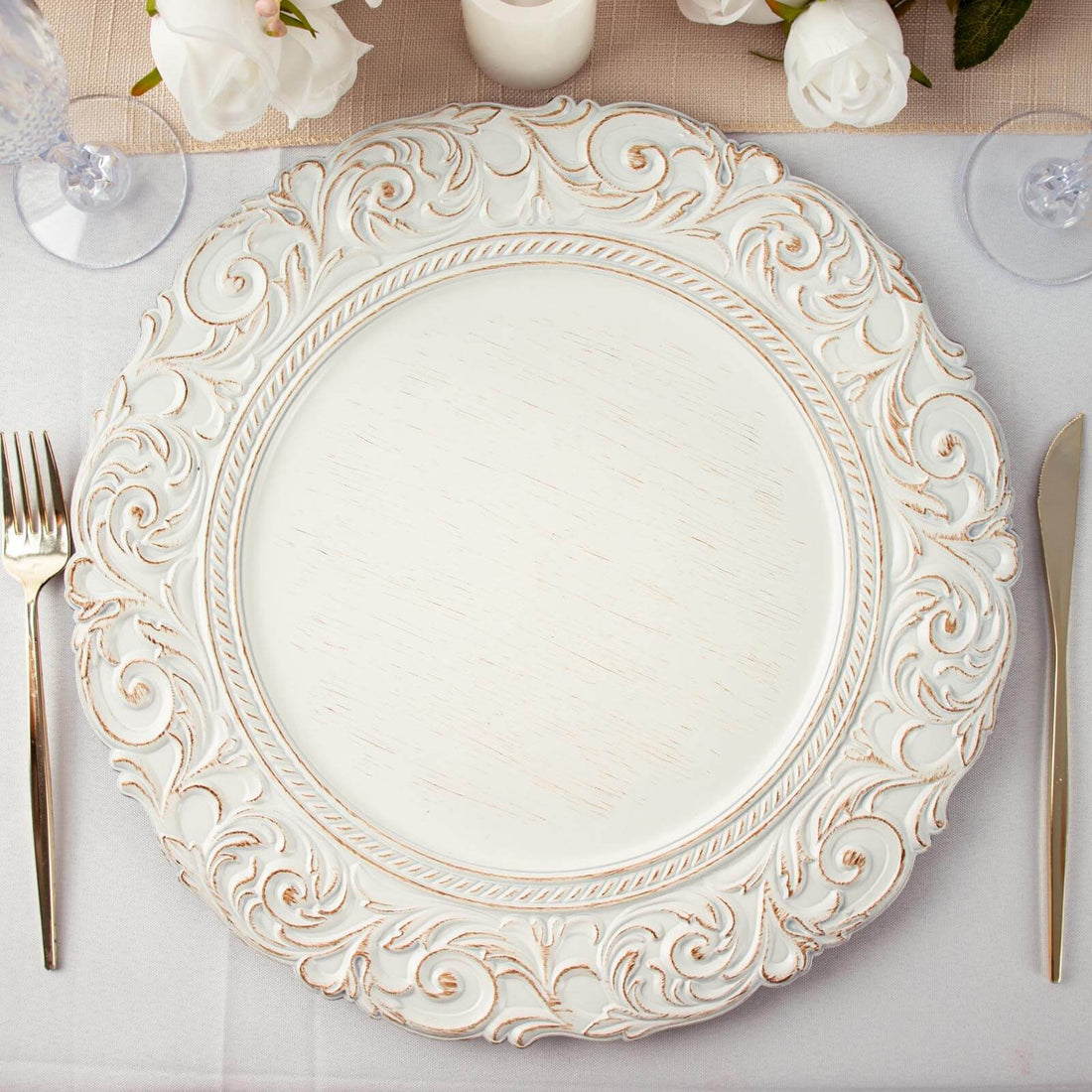 Ornate white decorative plate on a table setting with cutlery.