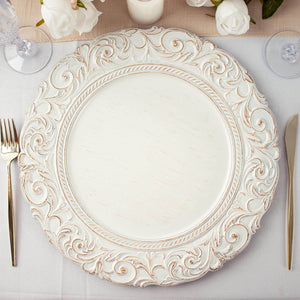 Ornate white decorative plate on a table setting with cutlery.
