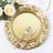 Elegant gold charger plate with ornate design, fork, and knife on a floral table setting.