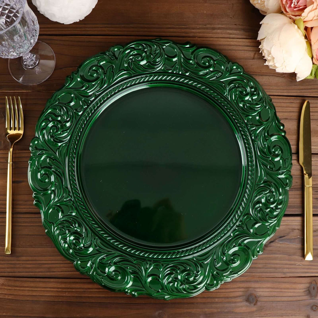 Green decorative charger plate on a wooden table with gold utensils.
