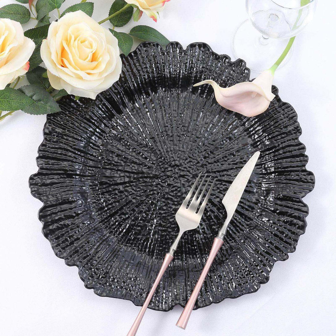 Black textured decorative plate with silver cutlery and floral accents.