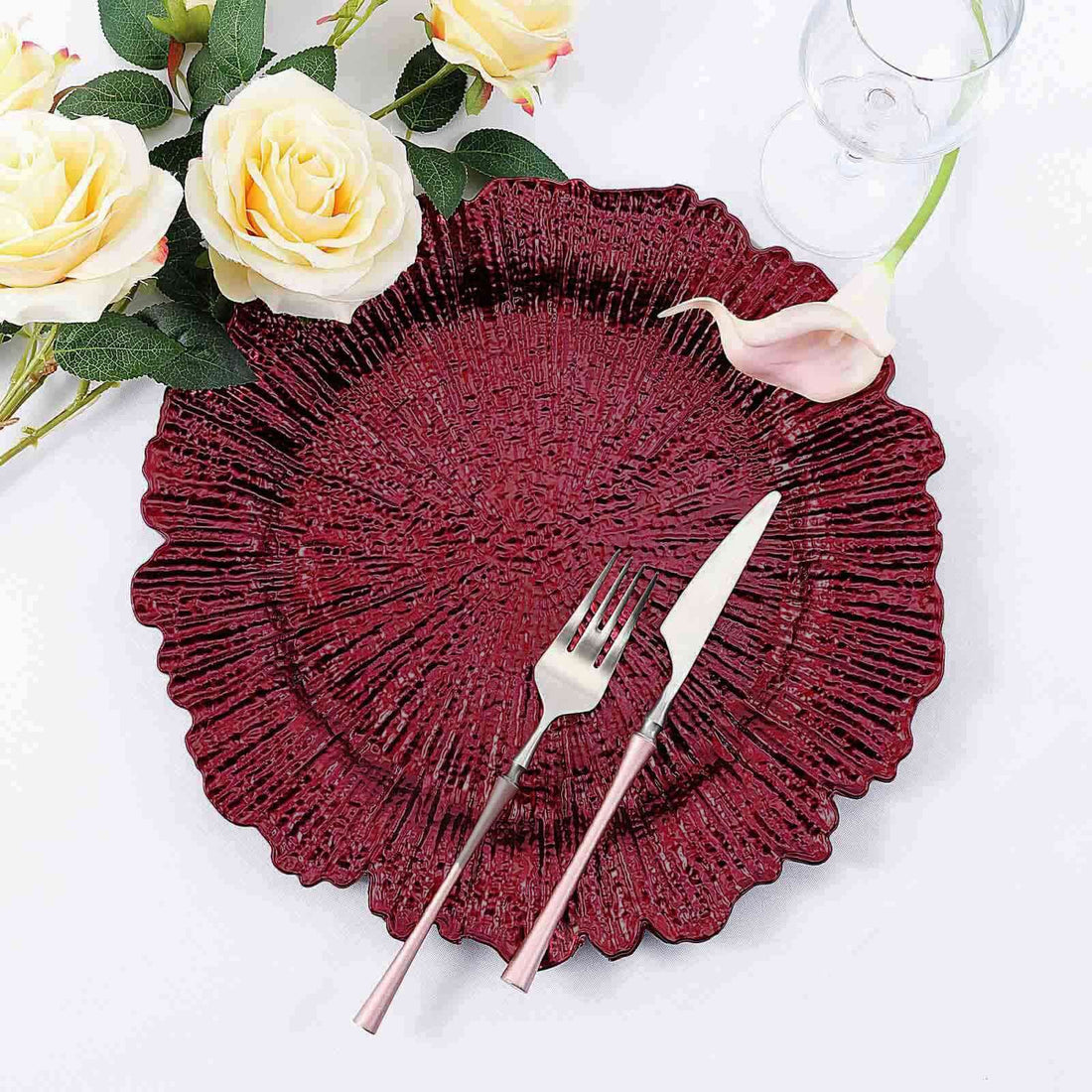 Elegant burgundy decorative plate with fork and knife, surrounded by flowers.