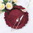 Elegant burgundy decorative plate with fork and knife, surrounded by flowers.