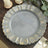 Gray decorative plate with gold accents on a wooden table.