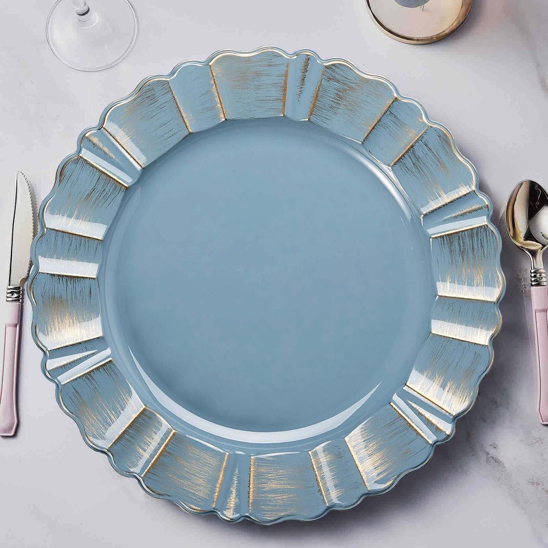 Blue decorative plate with gold accents on a marble table setting.