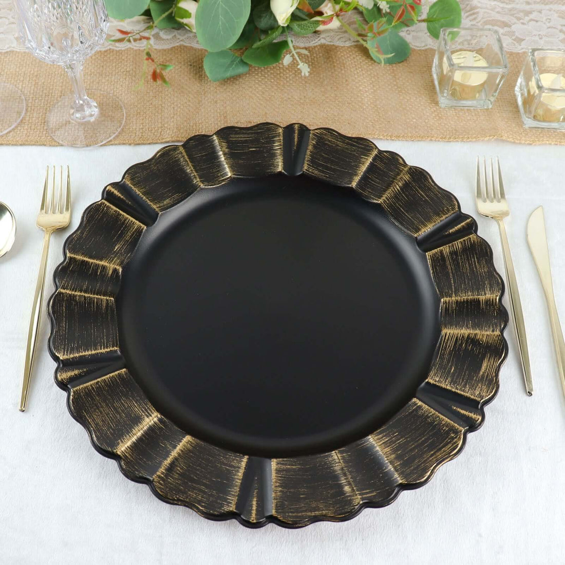 Black decorative plate with gold accents on a table setting.