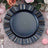 Navy blue decorative plate with scalloped edges on a pink glitter tablecloth.