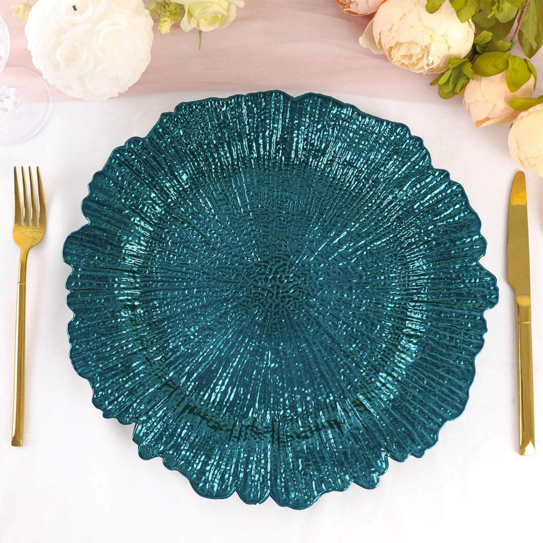 Teal decorative plate with textured design on a table setting.