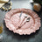 Rose gold decorative plate with cutlery on a textured surface.