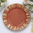 Decorative orange plate with gold trim on a textured table setting.