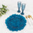 Blue decorative plate with two textured glasses and gold utensils on a marble surface.