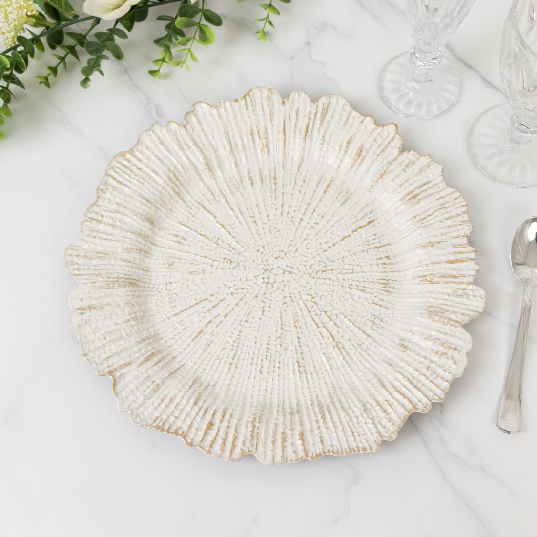Textured white decorative plate with a scalloped edge on a marble surface.