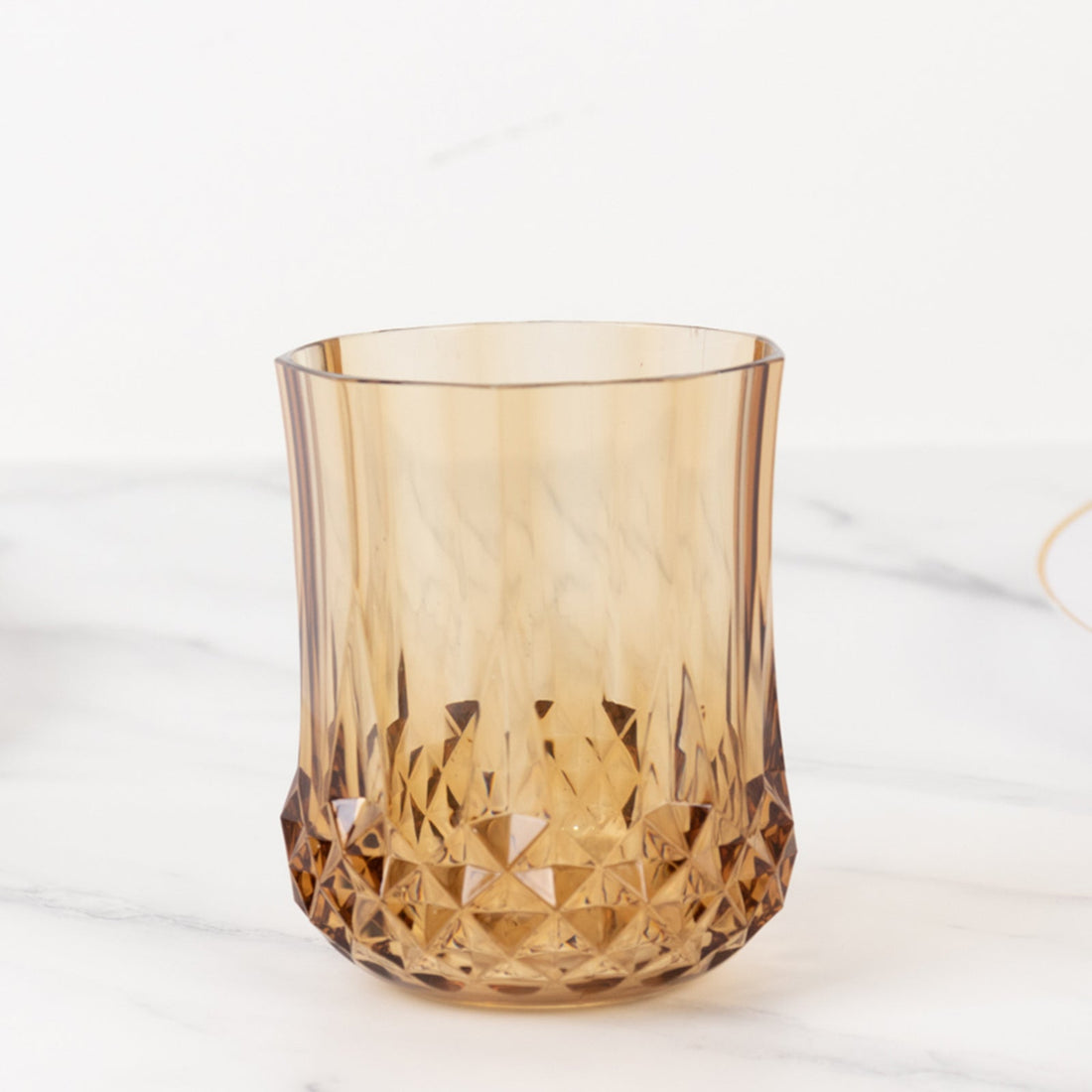 Amber geometric glass tumbler on a white background.