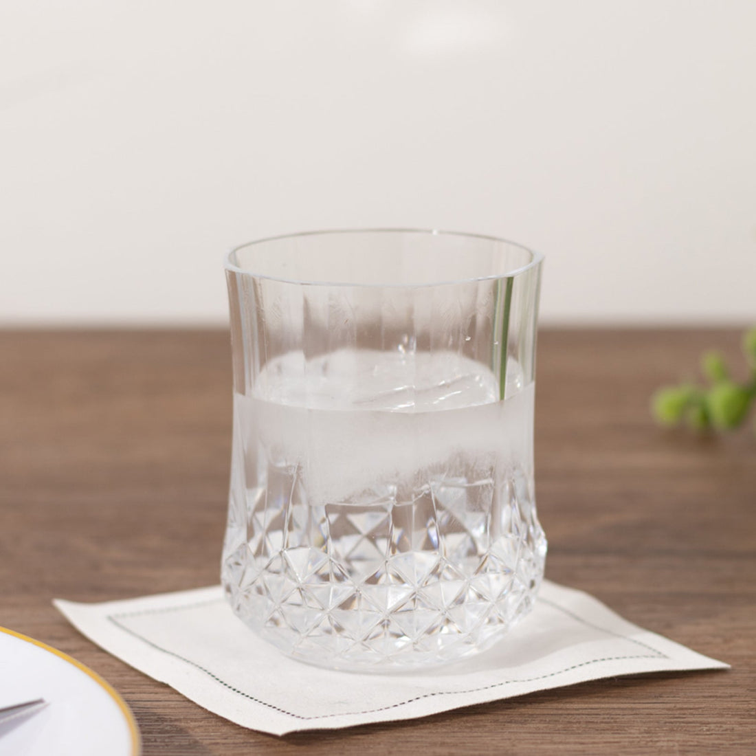 Crystal whiskey glass on a coaster with a drink inside.
