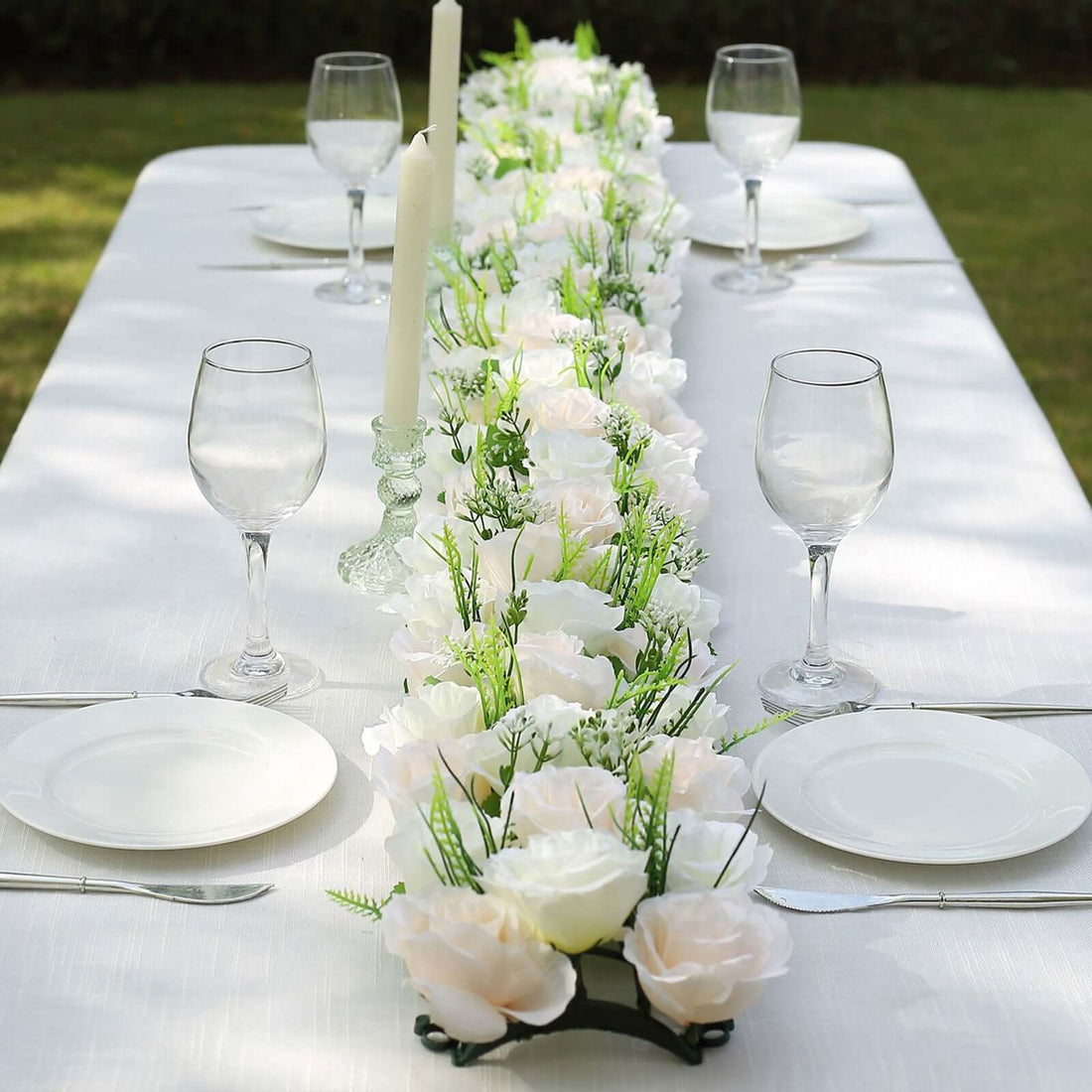 Elegant floral table centerpiece with candles and glassware for a dining setting.
