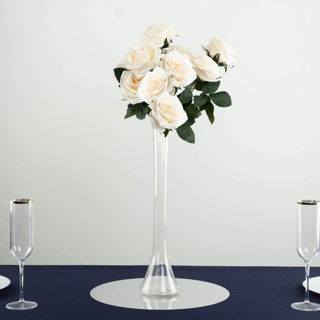 White rose bouquet in a tall glass vase on a table setting.
