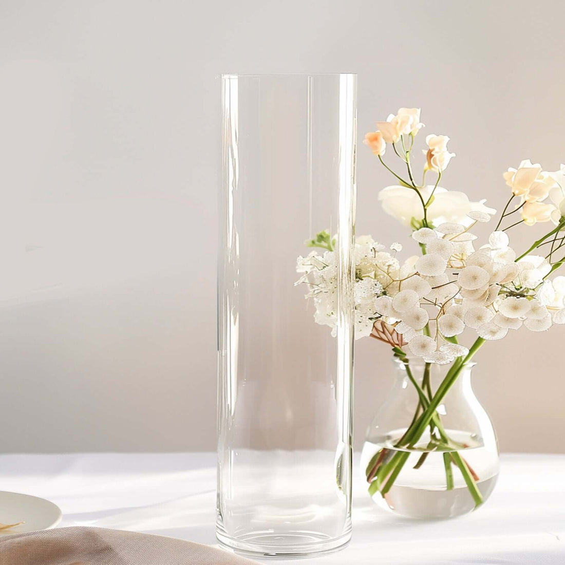 Tall, clear glass vase with delicate flowers arranged inside.