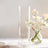 Tall, clear glass vase with delicate flowers arranged inside.