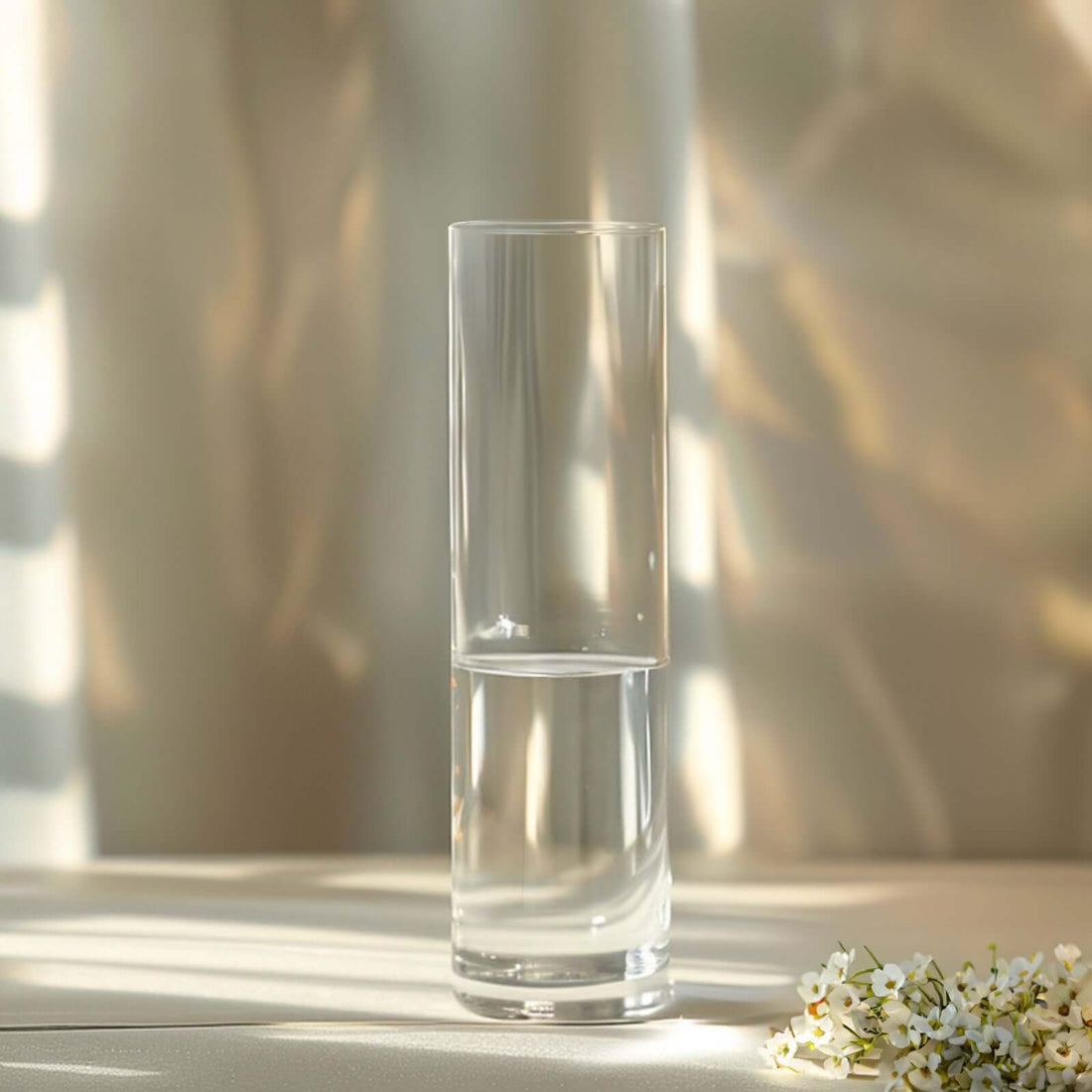 Elegant tall glass vase with water and floral accents.