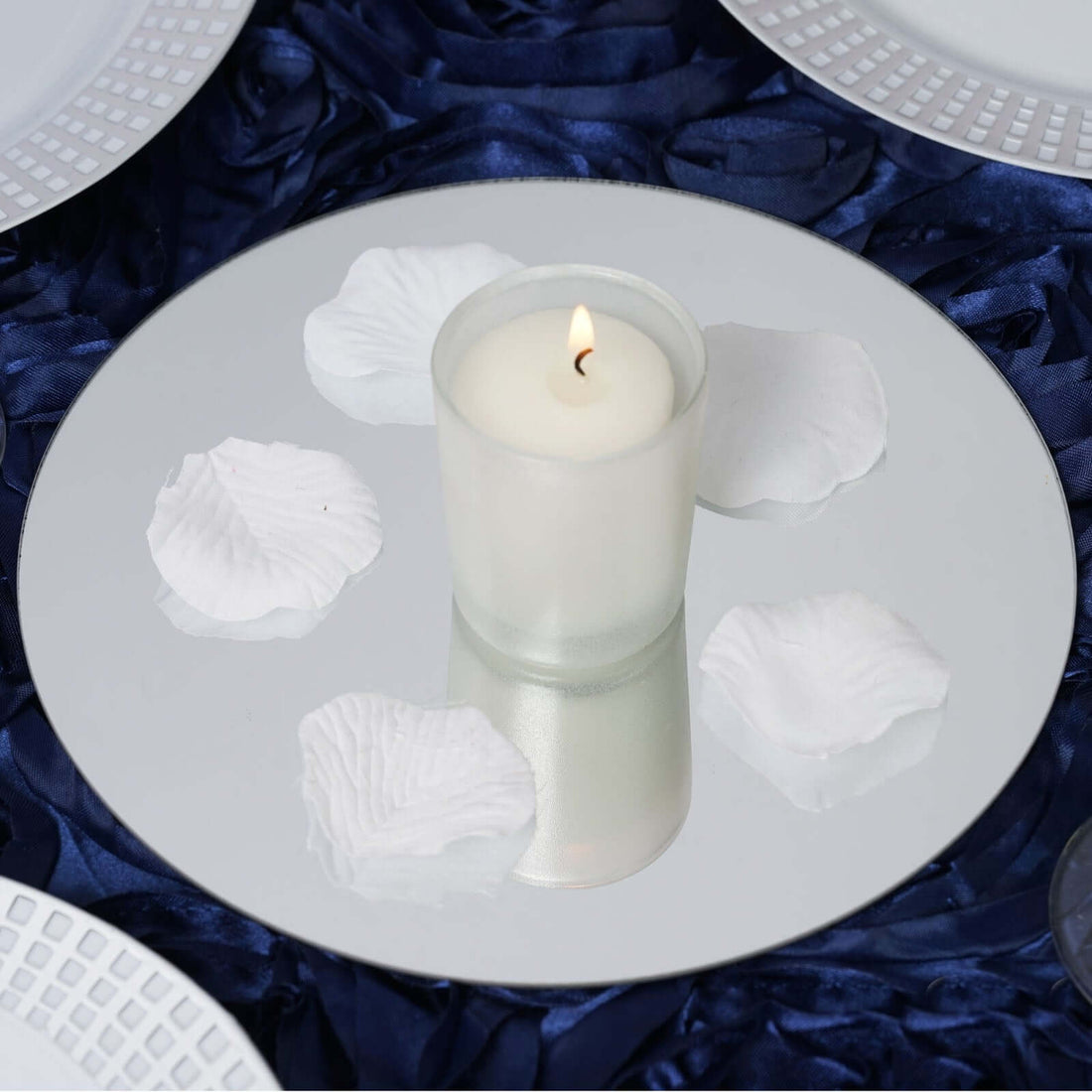 Candle centerpiece with white petals on a mirrored plate